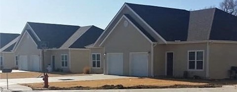 A row of houses with beige exteriors and dark roofs.