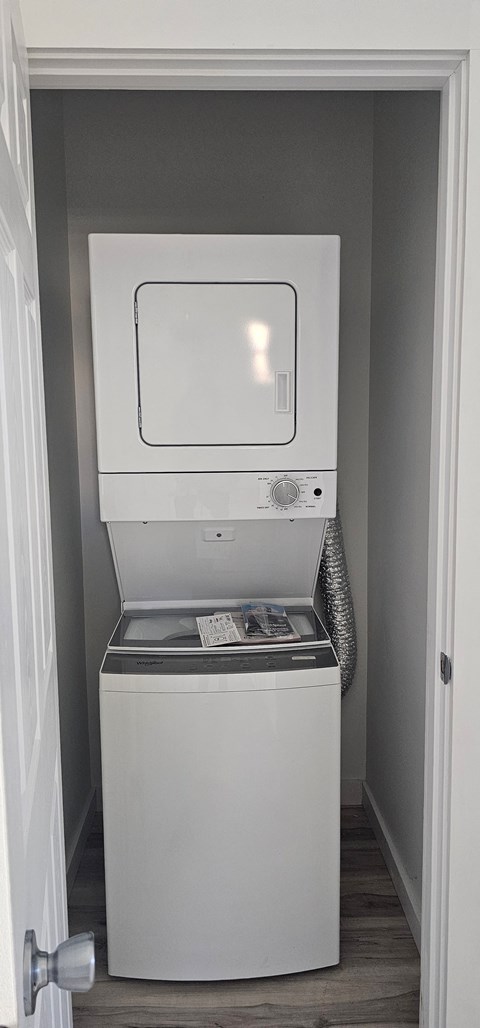 A white dishwasher is in a small, white-walled space.
