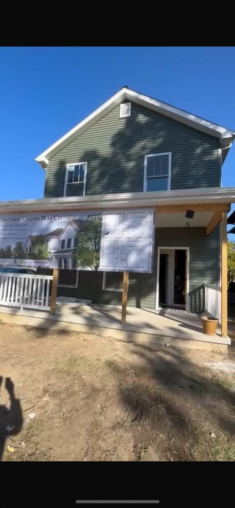 A house under construction with a banner on the front.