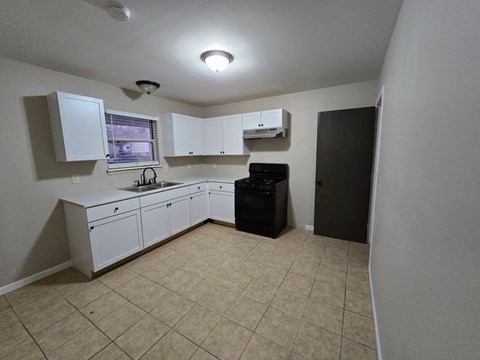 A kitchen with white cabinets and a black dishwasher.