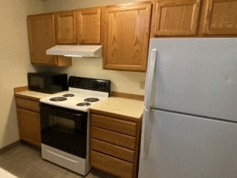 A white refrigerator sits next to a stove and oven in a kitchen.