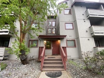 A white building with a red door and steps leading up to it.