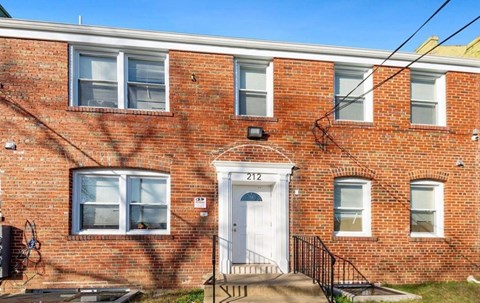 A red brick building with the number 212 on the front door.
