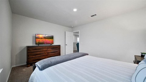 A bedroom with a bed, dresser, and painting on the wall.