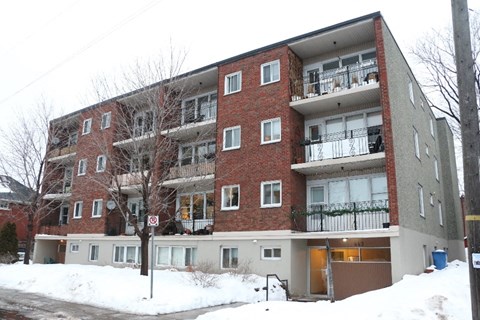 A red brick apartment building with a no parking sign in front.