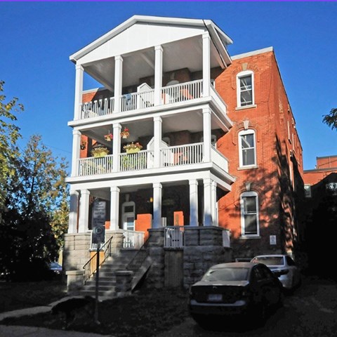 A two-story red brick house with a white balcony.