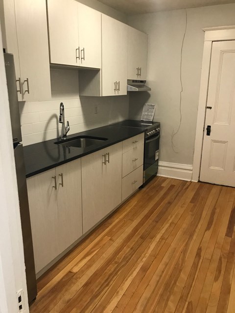 A kitchen with white cabinets and a black counter top.