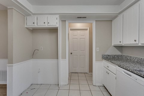 A kitchen with white cabinets and a doorway leading to another room.