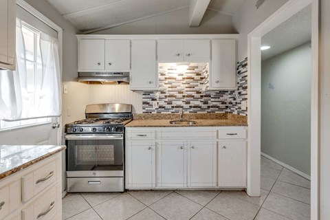 A kitchen with white cabinets and a tiled backsplash.
