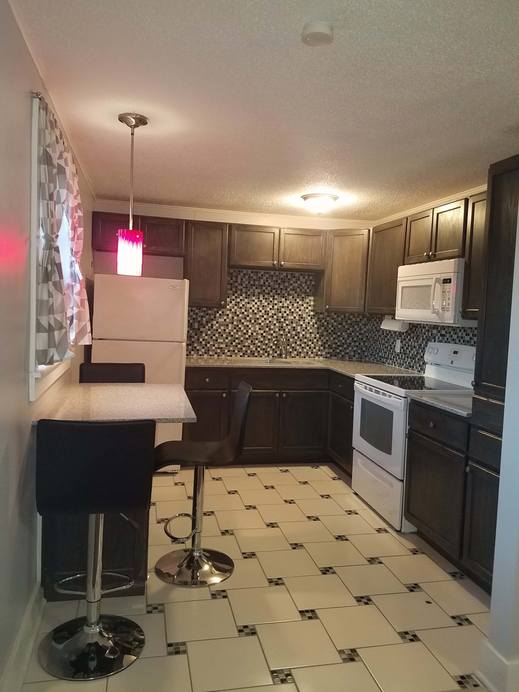 A kitchen with black and white tiles and a white refrigerator.
