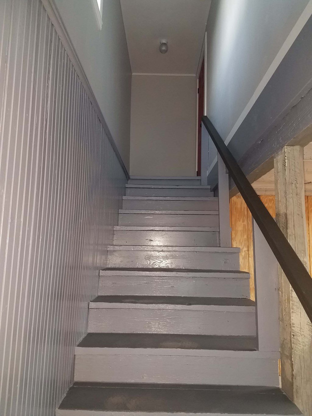 A staircase with a wooden handrail and grey steps.