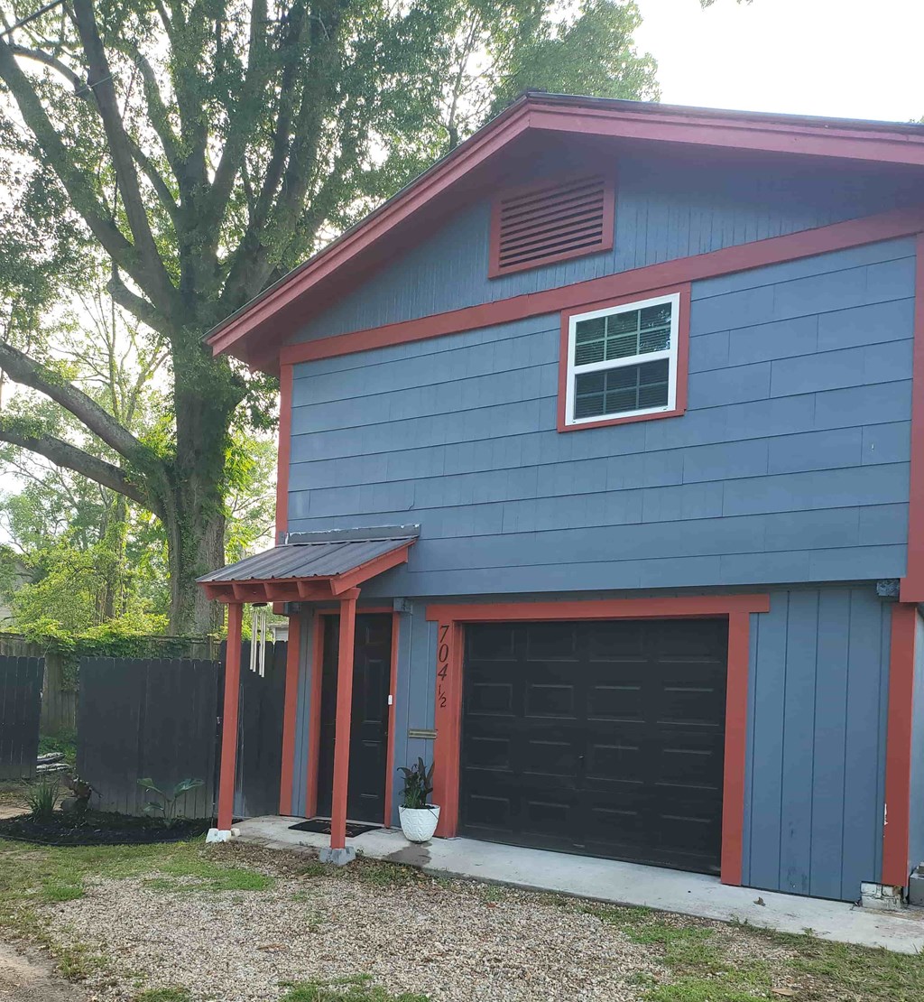 A blue house with a red roof and a black garage door.
