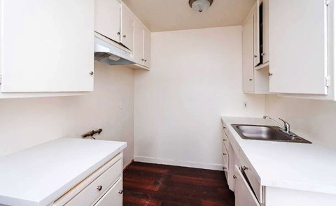 A small kitchen with white cabinets and a white counter top.