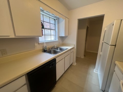 A kitchen with white cabinets and a black dishwasher.