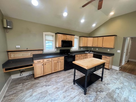 A kitchen with wooden cabinets and black countertops.