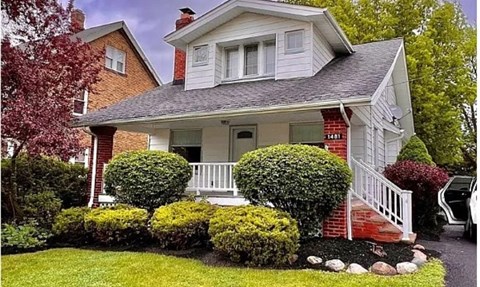 A house with a red brick chimney and a white porch.