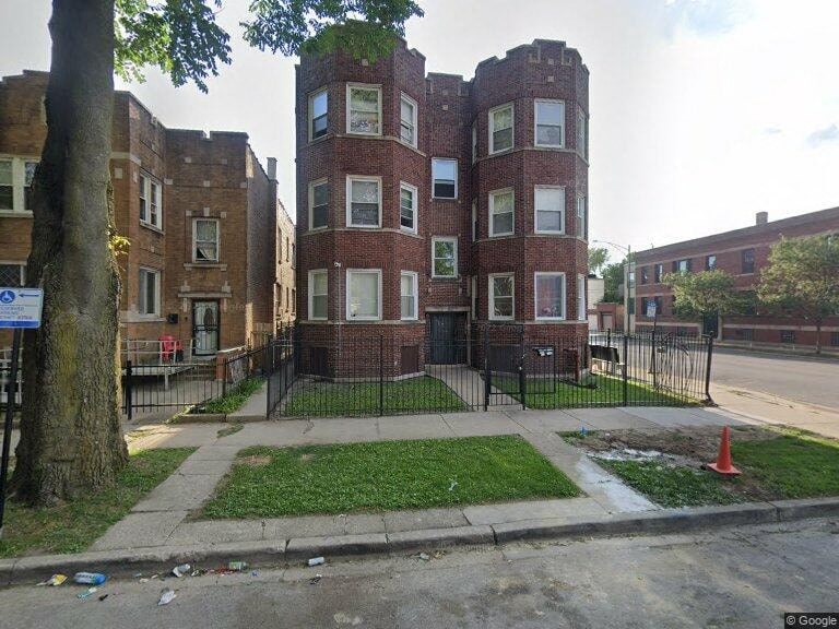 A red brick building with a black fence in front.