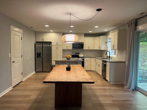 A kitchen with a wooden table in the middle of the room.