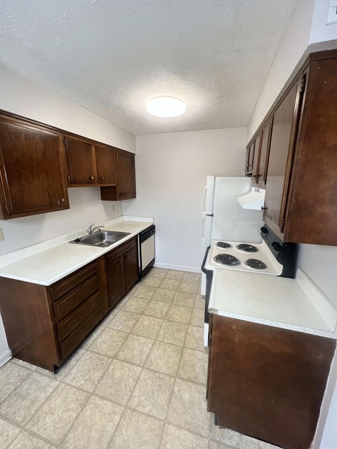 A kitchen with brown cabinets and a white fridge.