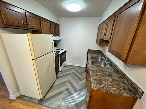 A kitchen with a white refrigerator and wooden cabinets.