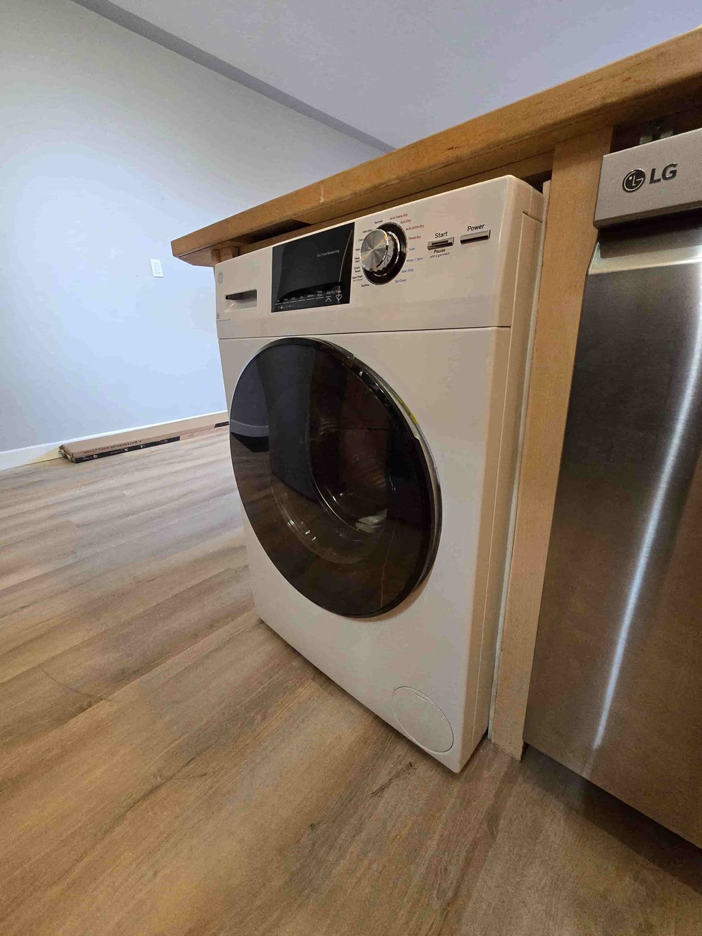 A white LG washing machine in a room with wooden flooring.
