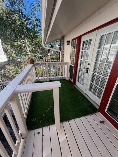 A white deck with a red door and a green lawn.