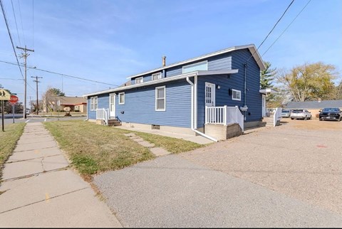 A blue house with a porch and a driveway in front.