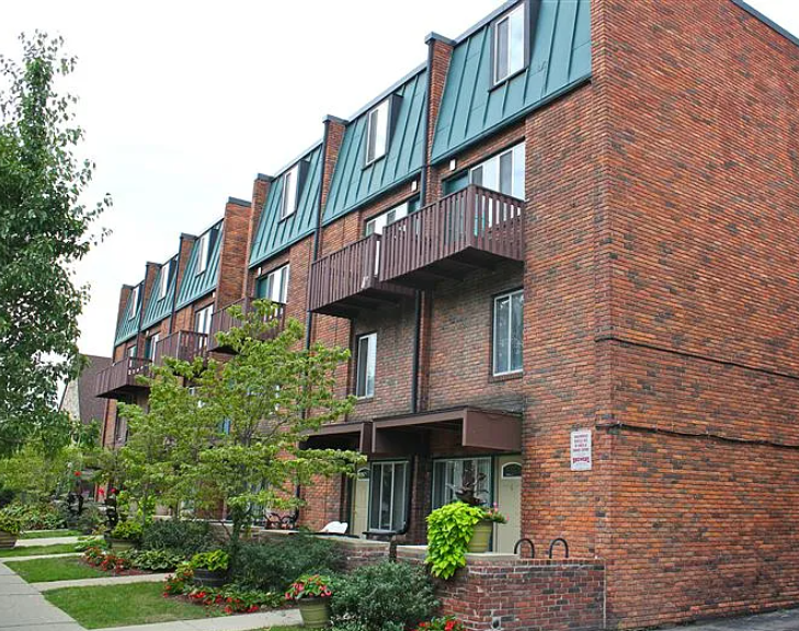 A red brick building with green trim and balconies.
