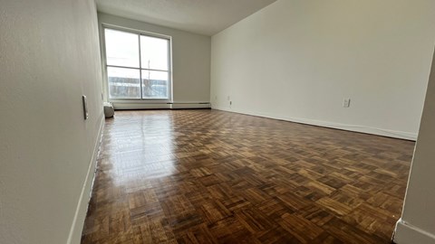 A room with wooden flooring and a large window.