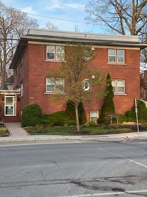 A red brick house with a tree in front.