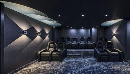 A dark cinema room with rows of seats and spotlights.
