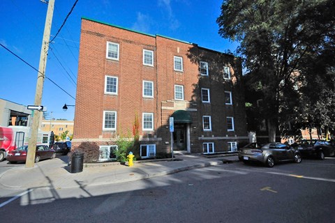 A red brick building with a green roof and a tree in front.