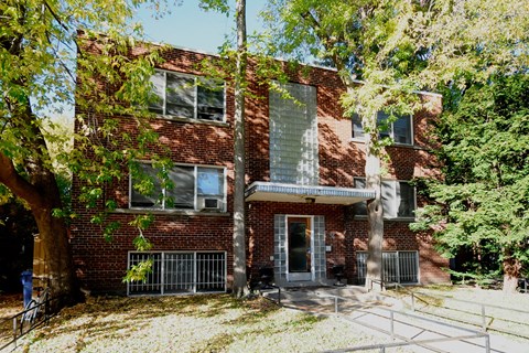 A red brick building with a tree in front of it.