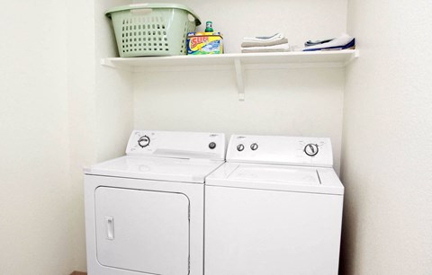 Two white front loading washing machines in a laundry room.