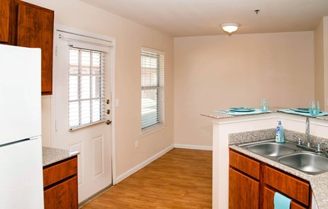 A kitchen with a white fridge, wooden cabinets, and a sink.