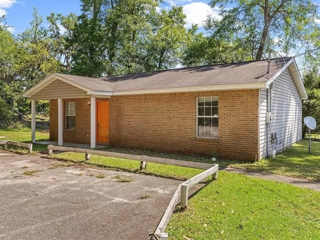 A small brick house with a red door and a white fence.