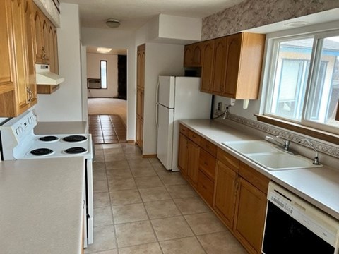 A kitchen with a white stove top oven and a white dishwasher.