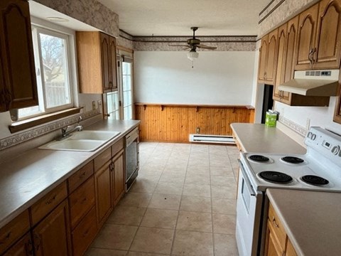 A kitchen with wooden cabinets and a white stove top oven.