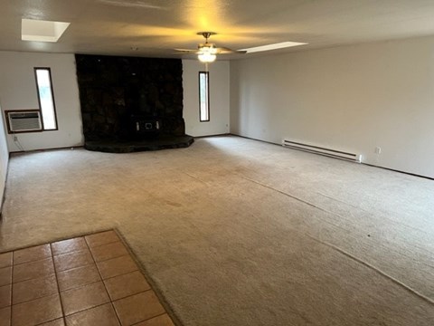 A spacious room with a fireplace and a carpeted floor.