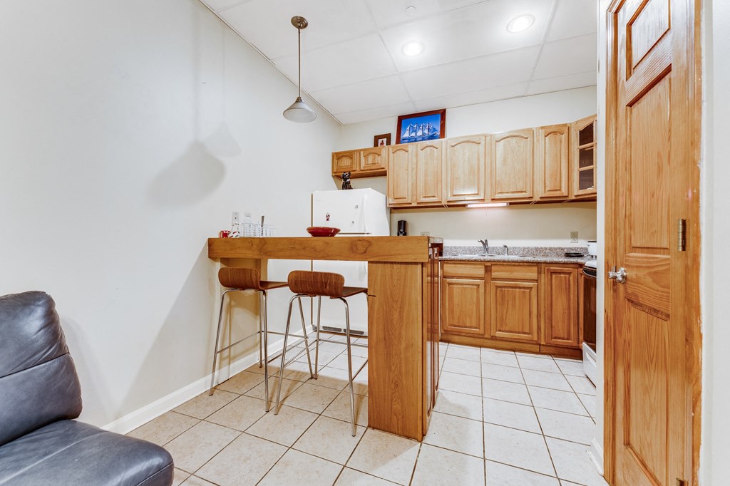 A kitchen with a bar stool and a grey leather chair.