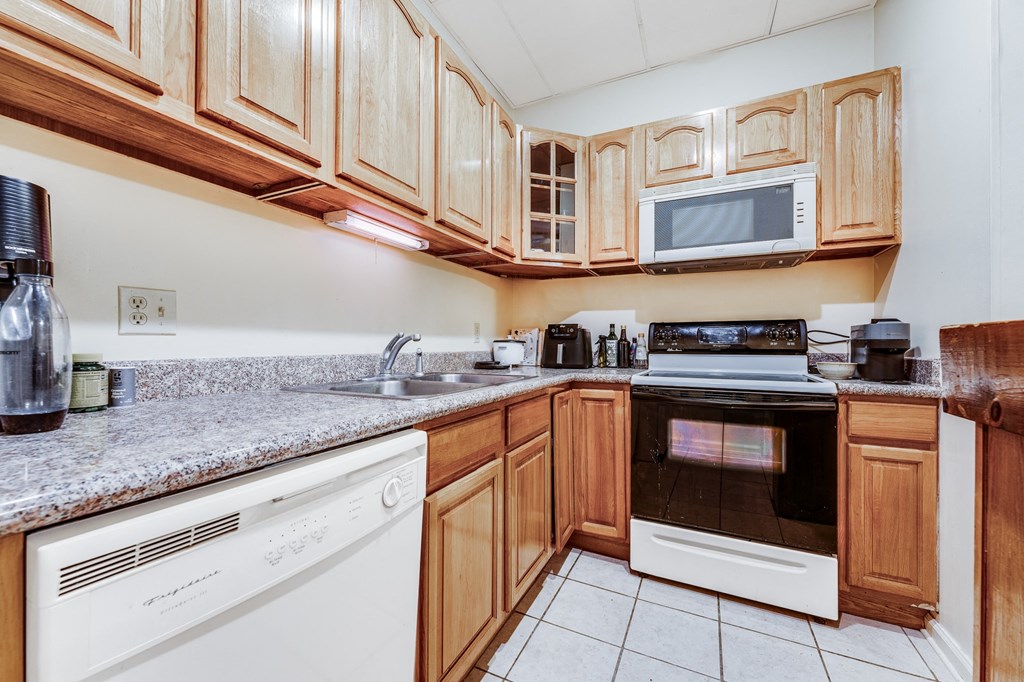 A kitchen with wooden cabinets and a white dishwasher.