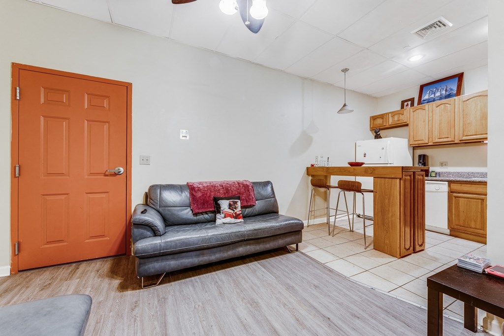 A living room with a grey couch and an orange door.