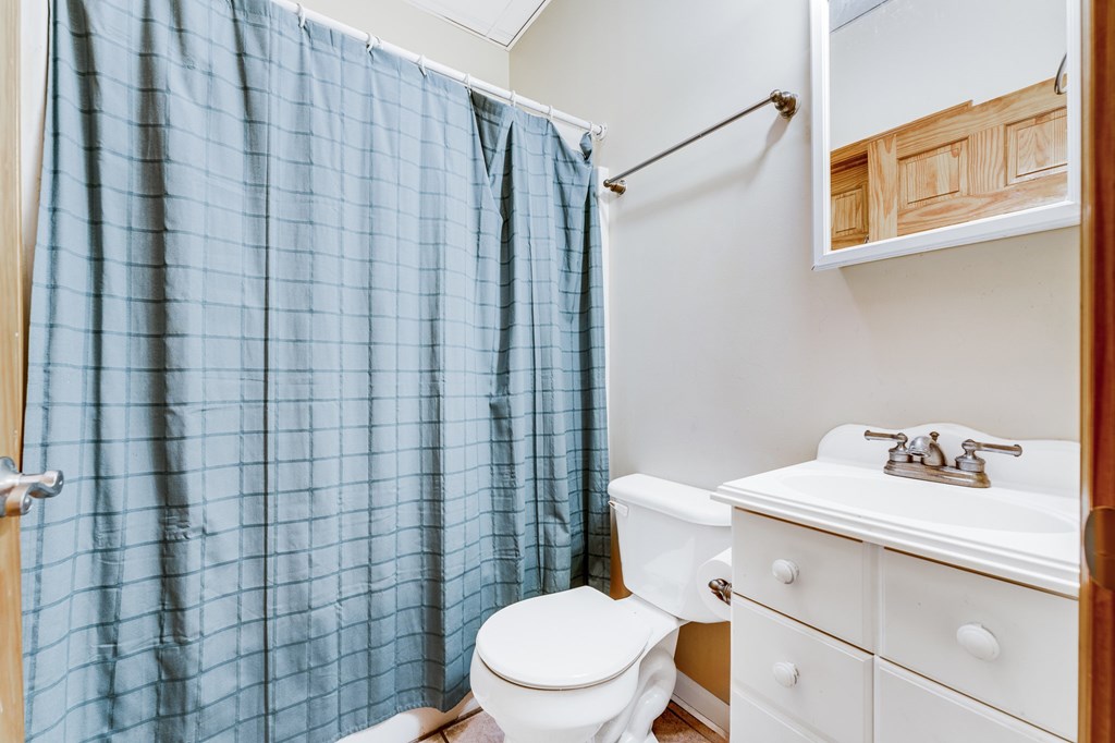 A bathroom with a white toilet, a white sink, and a blue shower curtain.