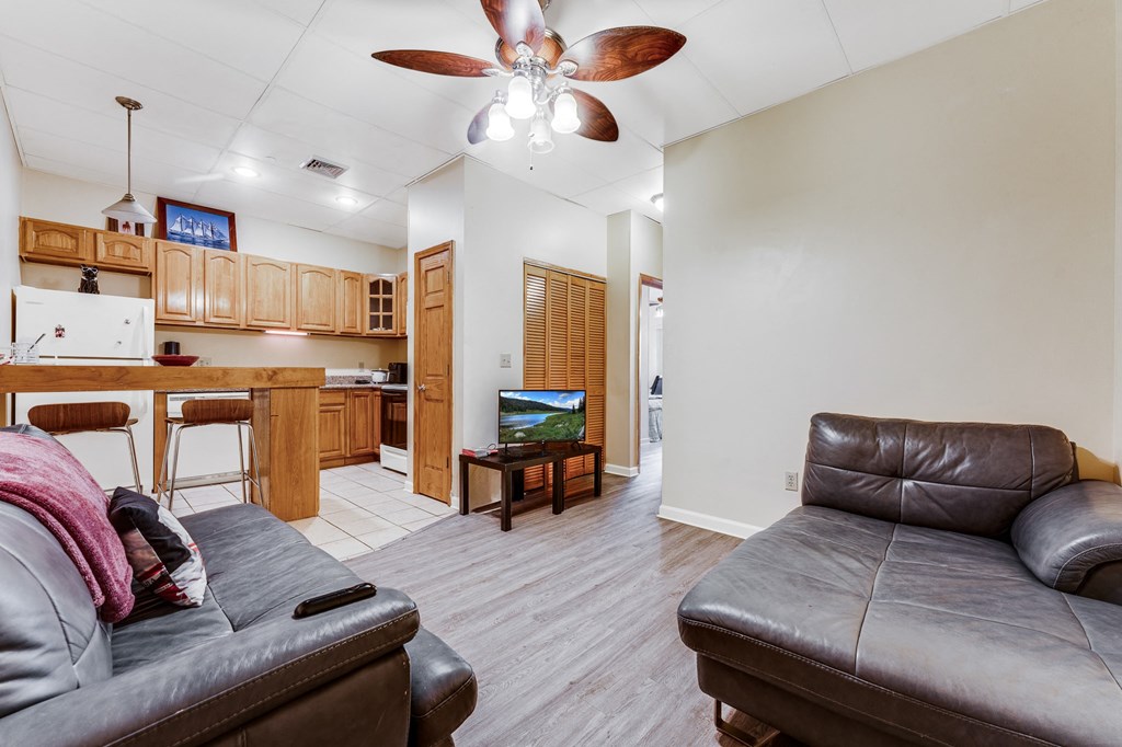 A living room with a grey couch and a ceiling fan.