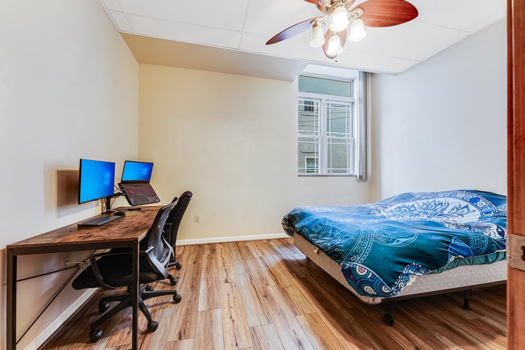A room with a bed, desk, and chairs.