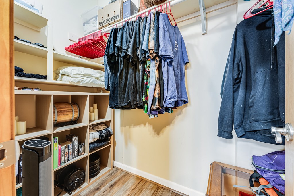 A room with a closet full of clothes and a shelf with shoes and other items.