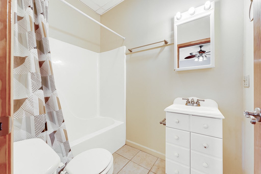 A white bathroom with a toilet, sink, and shower.