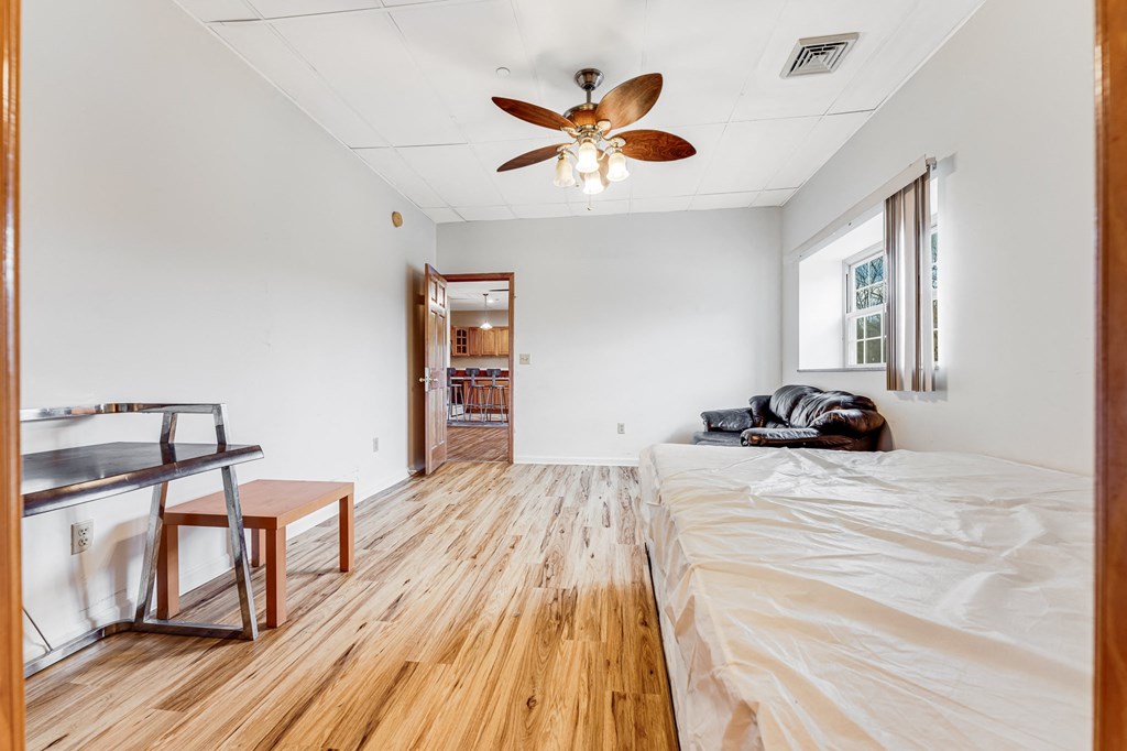 A room with a bed, a table and a ceiling fan.