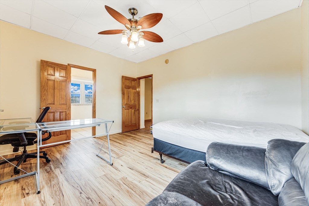 A room with a bed, a desk, and a ceiling fan.