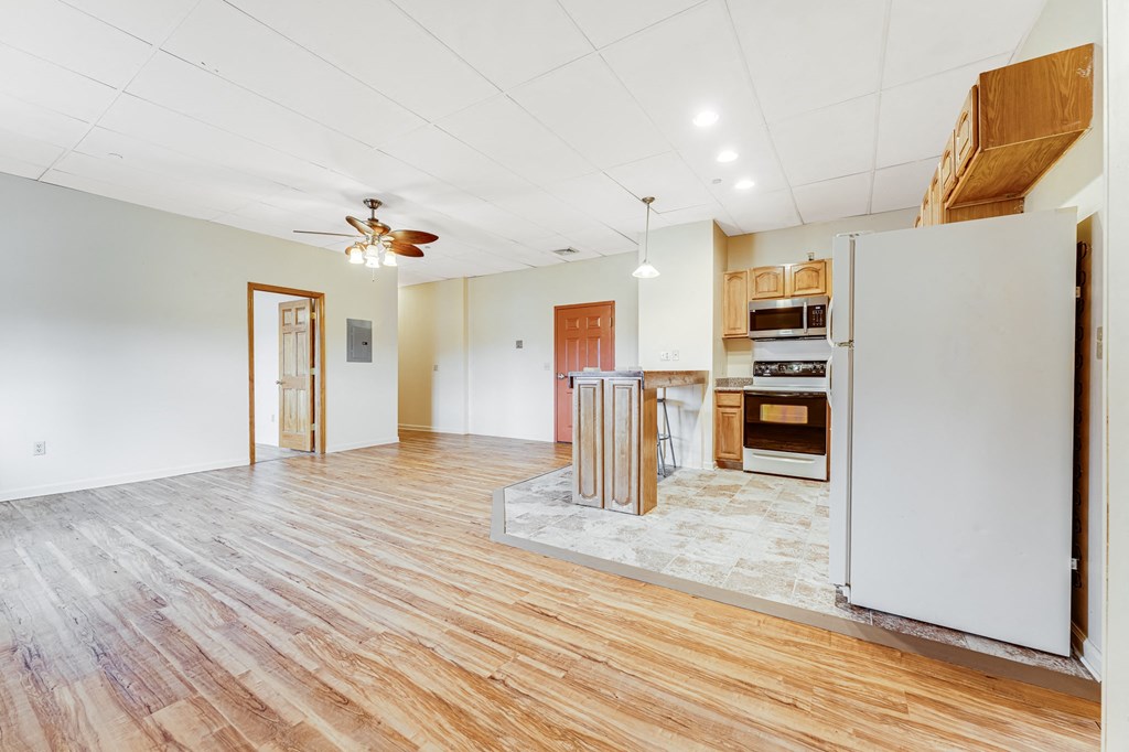 A kitchen with a white refrigerator and wooden floors.
